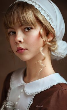 a woman with blonde hair wearing a white bonnet and brown dress is looking at the camera