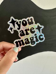 someone holding up a sticker with the words you are magic on it in front of a guitar