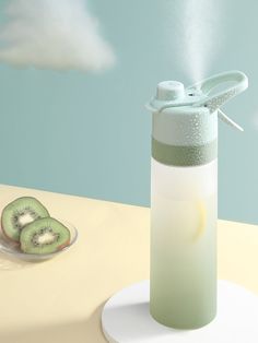 a green and white water bottle sitting on top of a table next to kiwi slices