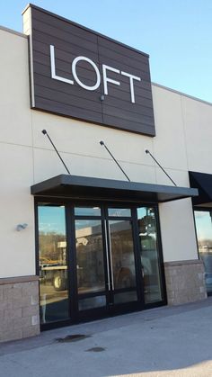 the front of a store with glass doors and black awnings that read loft