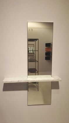 a mirror is hanging on the wall above a shelf