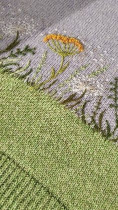 an embroidered piece of cloth with flowers and leaves on the side, sitting on top of a table