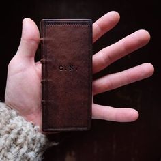 a hand holding a small brown book with the word love on it's cover