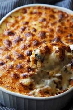 a spoon full of macaroni and cheese being lifted from a casserole dish