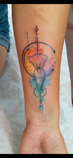 a woman's arm with a watercolor tattoo design on the left side of her wrist