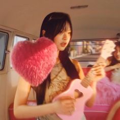 a woman in a car holding a pink guitar