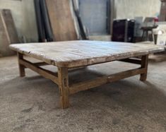 a wooden table sitting on top of a floor next to other pieces of furniture in a room