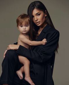 a woman holding a child in her lap and posing for the camera with one arm around another