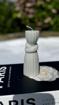 a white vase sitting on top of a book