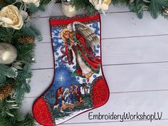 a christmas stocking with an angel on it next to some flowers and greenery