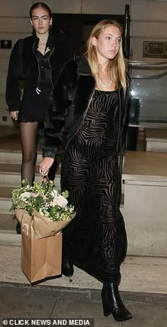 a woman in a long black dress carrying flowers