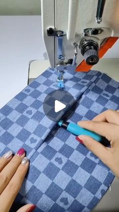 two hands are using a sewing machine to sew on a piece of blue fabric