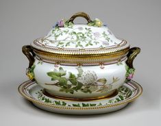 an ornately decorated tea pot and saucer with gold trimmings on the rim