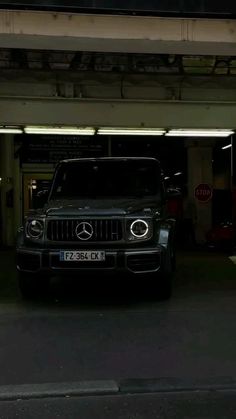 a car parked in front of a parking garage with its lights on and the door open