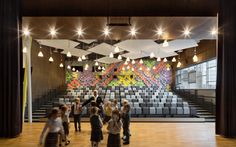 a group of children standing in front of an auditorium with chairs and lights on the ceiling