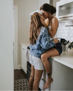 two young women are kissing in the kitchen