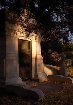 an old cemetery in the fall with leaves on the ground and trees around it at night