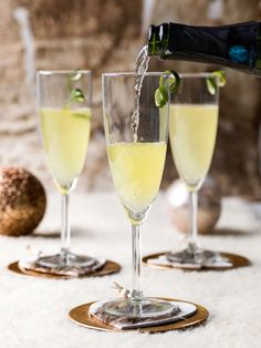 champagne being poured into three glasses on a table