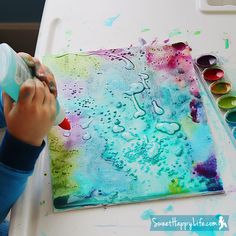 a little boy painting on a canvas with watercolors