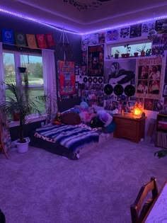 a bedroom with purple lights and pictures on the wall, bed in front of a window