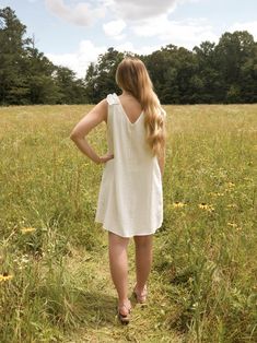 This is a white sleeveless v neck dress with a ruffle detail on the shoulder. The model is wearing a size small Feminine White V-neck Ruffle Dress, Feminine V-neck Ruffle Dress For Garden Party, Summer Sleeveless V-neck Dress With Ruffles, V-neck Ruffled Sundress For Daywear, Flowy V-neck Ruffle Dress For Garden Party, Summer V-neck Ruffle Dress For Garden Party, White V-neck Ruffle Dress For Day Out, Spring White Sleeveless Dress With Ruffle Hem, White Sleeveless Dress With Ruffle Hem For Spring