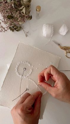 someone is working on an art project with yarn and thread, including dandelions