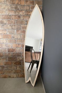 a mirror sitting on the side of a brick wall next to a desk and chair