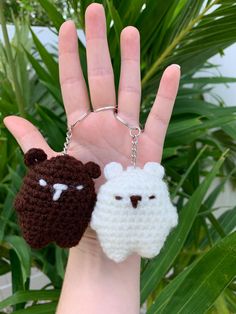 two crocheted sheep and bear keychains on a hand