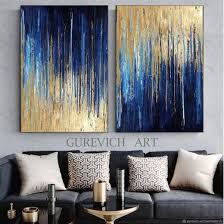 two paintings on the wall above a couch in a living room, one is blue and gold