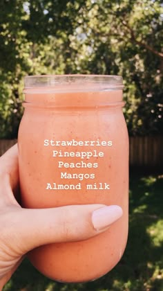 a hand holding a jar of strawberry pineapple peaches and almond milk with the words, strawberries pineapple peaches mangos almond milk