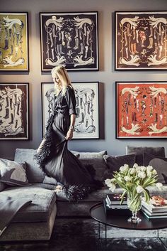 a woman is standing in the middle of a living room with art on the wall