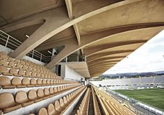 an empty stadium filled with lots of seats next to a green field and grass covered field