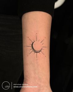 a small sun tattoo on the wrist that is black and white, with lines running through it