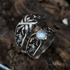 a silver ring with an opal in the center on top of a piece of wood