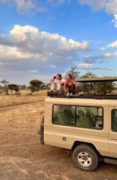 two people sitting on the roof of a vehicle