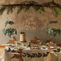 a table topped with a cake next to a tree branch hanging from it's ceiling