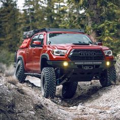 a red toyota truck driving down a dirt road