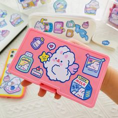 a person holding up a pink case with stickers on it