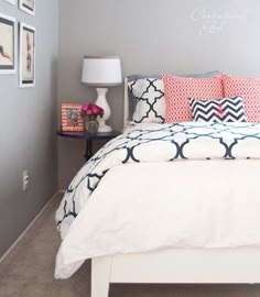 a white bed topped with pillows next to a night stand