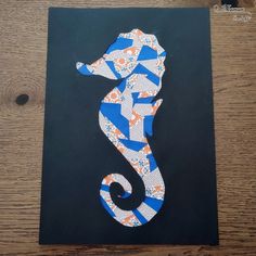 a blue and white seahorse on a black paper with orange, white, and blue stripes