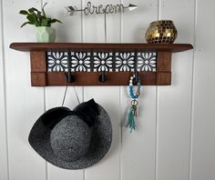 a hat hanging on a wooden shelf next to a wall