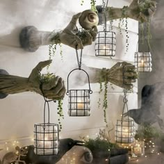 several hands are holding small cages with plants in them and lights hanging from the ceiling