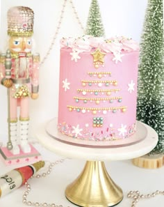 a pink christmas cake sitting on top of a table next to a nutcracker