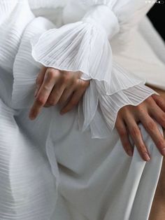 a woman in white dress with her hands on the skirt