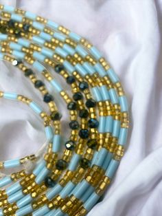 Single Strand Waist Bead Senoufo harmonizes the beauty of light blue crystal glass seed beads with the timeless elegance of gold glass seed beads. This handcrafted masterpiece captures the essence of sophistication, inviting you to adorn yourself with grace and style. 🌊 Light Blue Crystal Glass Seed Beads: Reflecting the tranquil hues of the sky and sea, the light blue beads exude calm and serenity. Blue signifies wisdom and clarity, empowering you with a sense of purpose. 🌟 Gold Glass Seed Be Blue Colorful Waist Beads As Gift, Blue Beaded Waist Beads As Gift, Blue Artisan Jewelry With Tiny Beads, Artisan Blue Jewelry With Tiny Beads, Artisan Gold Beaded Bracelets With Colorful Beads, Blue Waist Beads With Spacer Beads As Gift, Blue And Gold Beads For Jewelry Making, Blue Round Beads Waist Beads For Gift, Bohemian Light Blue Jewelry With Faceted Beads