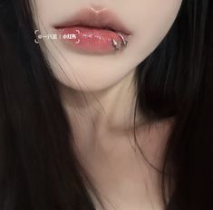 a woman with long black hair and piercings on her lips