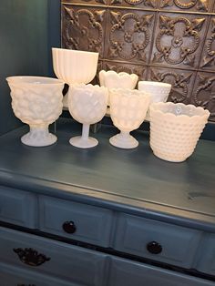 several white vases sitting on top of a blue dresser