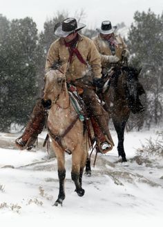 two men are riding horses in the snow