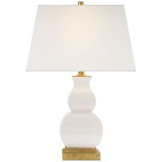 a white table lamp with a gold base and a white linen shade on the top