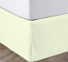 a bed with a light green cover and white sheets on it's bottom half